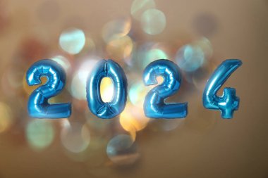 Yeni yıl 2024. Açık kahverengi arkaplanda bulanık ışıklı mavi numara şekilli balonlar.