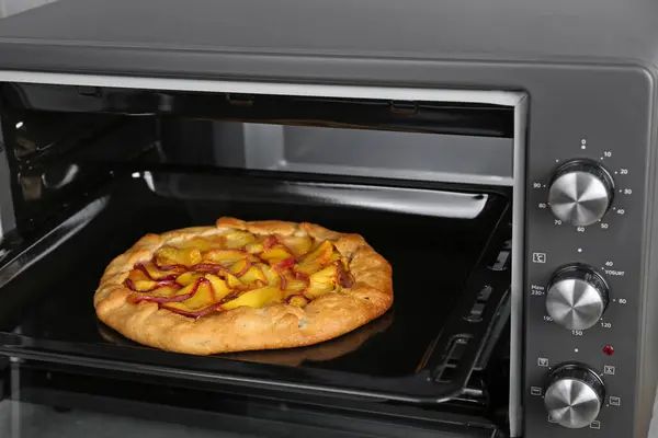 Open electric oven with delicious pie, closeup