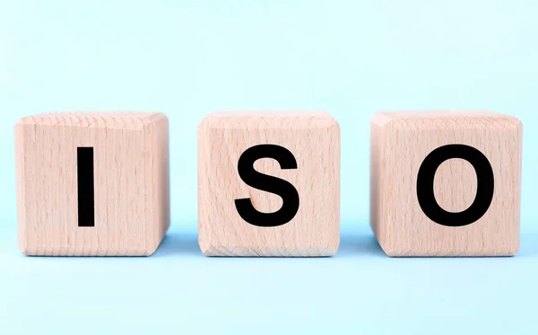 International Organization for Standardization. Wooden cubes with abbreviation ISO on light blue background, closeup