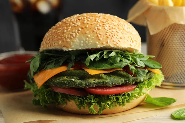 Tasty vegetarian burger with spinach cutlet, cheese and vegetables served on white table, closeup
