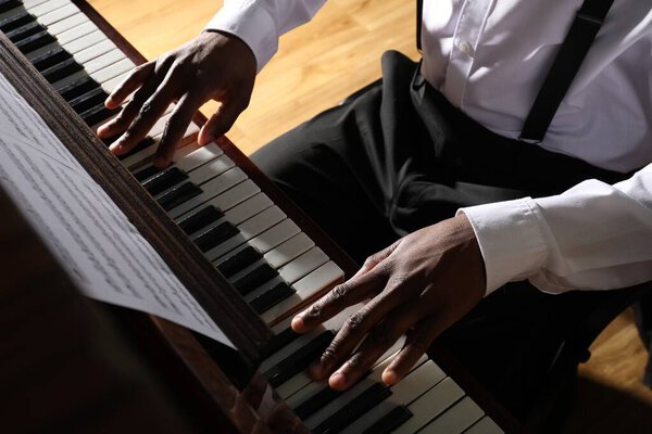 Афроамериканец играет на пианино в помещении, крупным планом. Талантливый музыкант