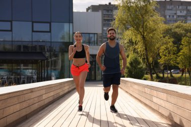 Sağlıklı bir yaşam tarzı. Güneşli bir günde dışarı koşan mutlu çift