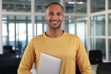 Ofisinde dizüstü bilgisayarı olan yakışıklı mutlu adam.