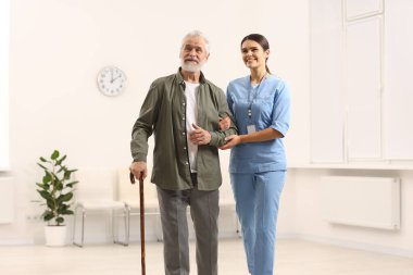 Hastanede yaşlı hastalara bakan gülümseyen hemşire.