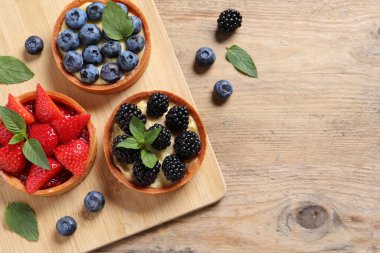 Tahta masada farklı taze böğürtlenli turtalar, düz yatak ve metin için yer. Tatlı nefis.