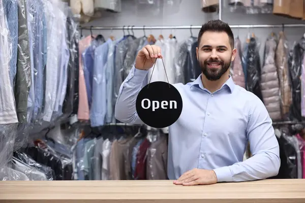Kuru temizleme servisi. Mutlu işçi açık levhayı kapalı mekanda tutuyor, mesaj için boşluk