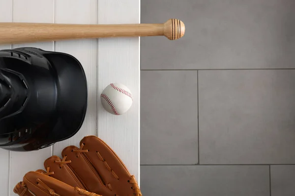 Baseball bat, batting helmet, leather glove and ball on white wooden bench indoors, top view. Space for text