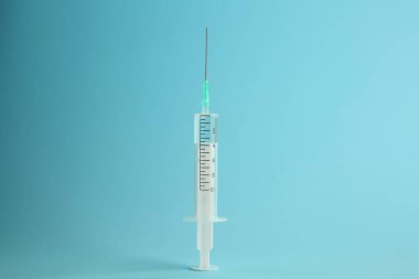 Açık mavi zemin üzerinde sıvı bulunan tıbbi şırınga