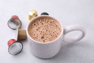 Bir fincan kahve ve kapsüller ışık masasında, yakın plan.