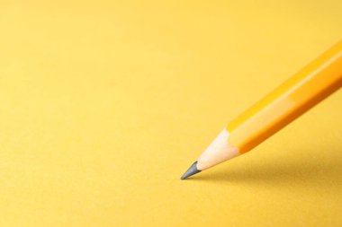 Sarı arka planda keskin bir grafit kalem, yakın plan. Metin için boşluk