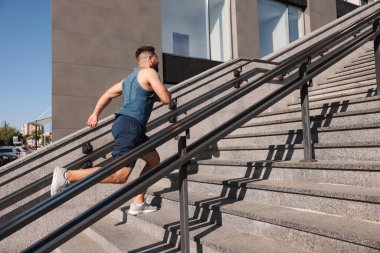 Güneşli bir günde merdivenlerden koşarak çıkan bir adam.