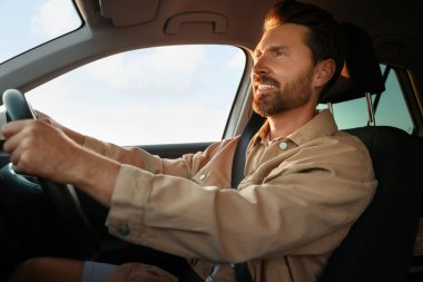 Arabasında oturan mutlu adam, düşük açılı. İyi yolculuklar.