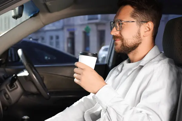 Coffee to go. Handsome man with paper cup of drink in car, space for text