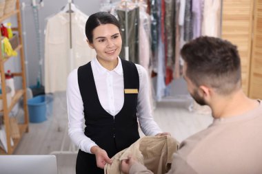 Kuru temizleme servisi. İçerideki müşteriden palto alan mutlu işçi.