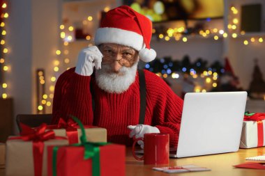 Noel Baba, Noel için dekore edilmiş odasındaki iş yerinde laptop kullanıyor.