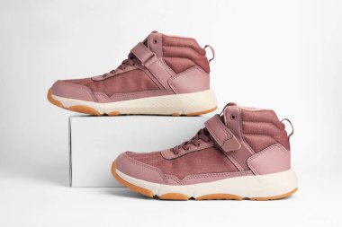 Bir çift şık çocuk ayakkabısı ve beyaz arka planda bir kutu.