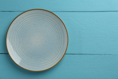 Açık mavi ahşap masadaki güzel seramik tabak, üst manzara. Metin için boşluk