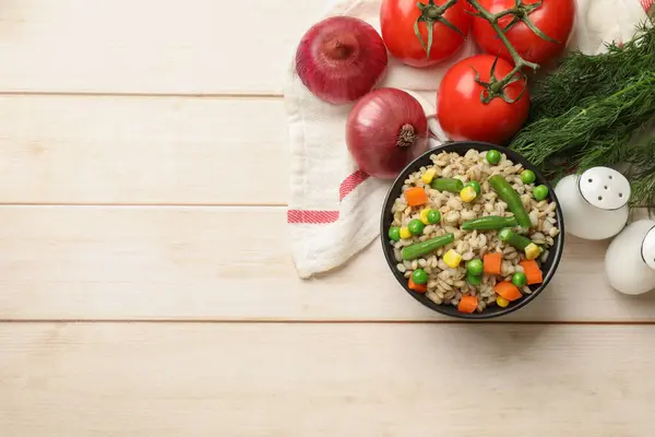 Delicious pearl barley with vegetables and other products on wooden table, top view. Space for text