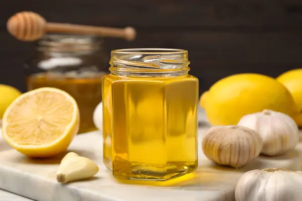 Jar with honey, garlic and lemons on table, closeup