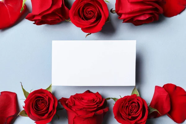 Leere Karte Schöne Rote Rosen Und Blütenblätter Auf Grauem Hintergrund lizenzfreie Stockbilder