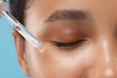 Kadın yüzüne serum uyguluyor, yakın plan.