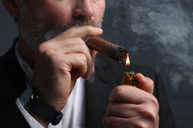 Koyu gri arka planda puro yakan sakallı adam, yakın plan.