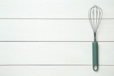 Beyaz ahşap masadaki metal çırpı, üst manzara. Metin için boşluk
