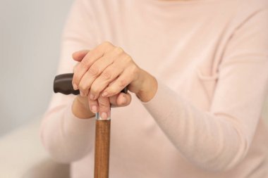 Bulanık arka planda bastonu olan olgun bir kadın, yakın plan.