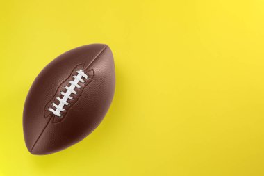 Sarı arka planda Amerikan futbol topu, üst manzara. Metin için boşluk