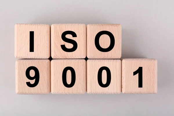 International Organization for Standardization. Wooden cubes with abbreviation ISO and number 9001 on light grey background, flat lay