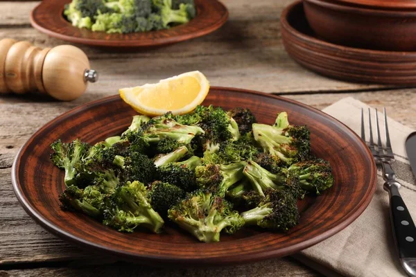 Tasty fried broccoli with lemon served on wooden table
