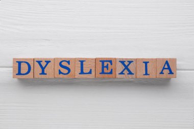 Beyaz ahşap masada kelime disleksisi olan küpleri düz yatıyordu.