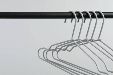 Boş elbiseler siyah askıda açık gri arka planda asılı, yakın plan. Metin için boşluk