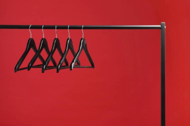 Siyah elbiseler kırmızı arka planda asılı duruyor. Metin için boşluk