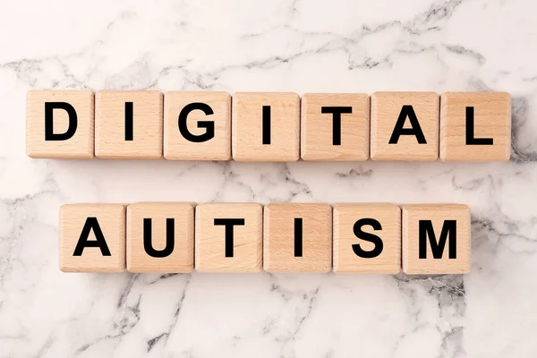 Phrase Digital Autism made of wooden cubes on white marble table, top view