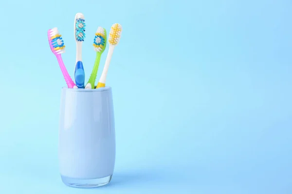 Different toothbrushes in holder on light blue background. Space for text