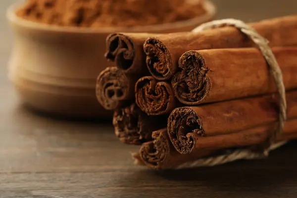 Dry aromatic cinnamon sticks on wooden table, closeup