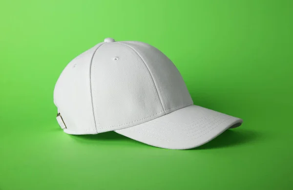 Stylish white baseball cap on light green background
