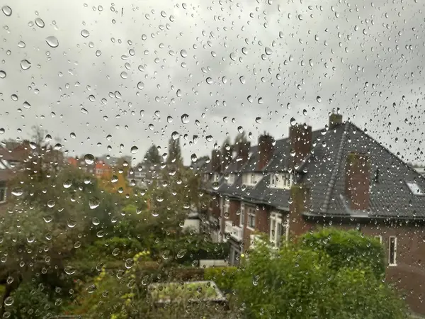 View on city street through window with water droplets on rainy day, closeup