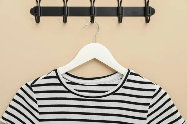 Hanger with striped t-shirt on beige wall