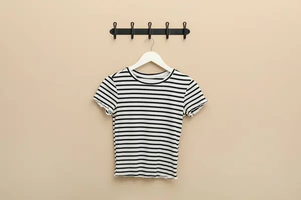 Hanger with striped t-shirt on beige wall
