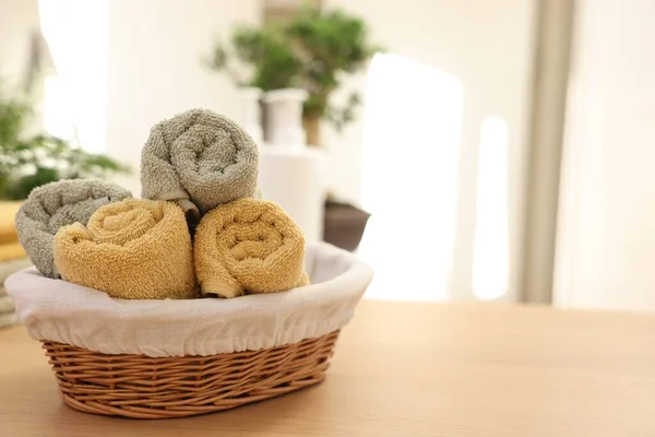 Basket with towels on wooden table indoors, space for text. Spa time