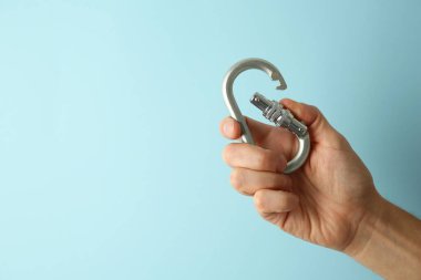 Açık mavi arka planda metal karabinalı adam, yakın plan. Metin için boşluk