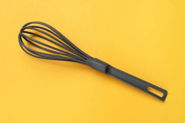 Sarı arka planda plastik çırpı, üst manzara. Mutfak aracı