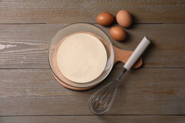 Metal çırpma, kasede hamur ve tahta masada yumurta, düz uzanma