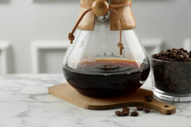 Cam kimya kahve makinesi, beyaz mermer masada kahve ve fasulye, yakın plan. Metin için boşluk