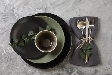 Masa dekorları çok şık. Tabaklar, çatal bıçak takımı, peçete ve çiçek dekoru.