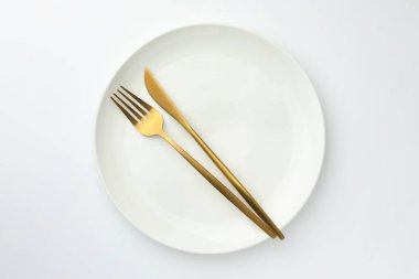Plate, fork and knife on white background, top view