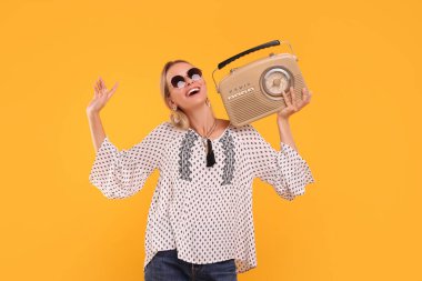 Sarı arka planda retro radyo alıcısı olan mutlu hippi kadın portresi.