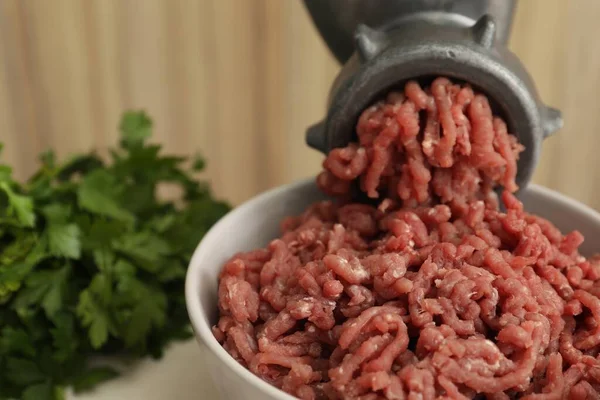 Mincing beef with manual meat grinder at table, closeup